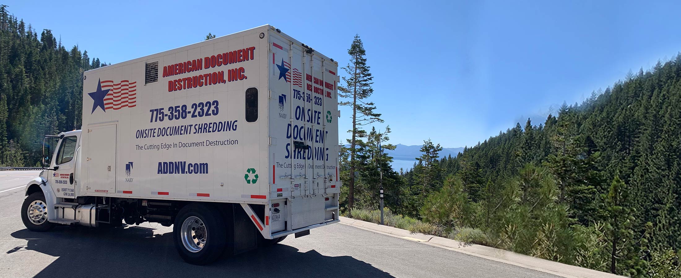 American Document Destruction shredding truck on the road with mountains and sky in background